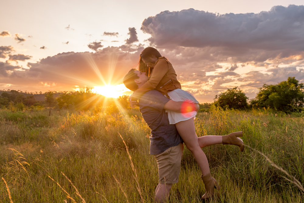 townsville engaged couple in a field embracing as the sun sets - wedding and engagement photography by Jamie Simmons
