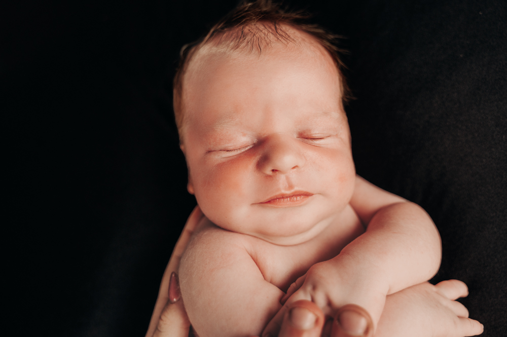 close up shot of newborn baby's face against a black blanket - newborn baby photography by Jamie Simmons