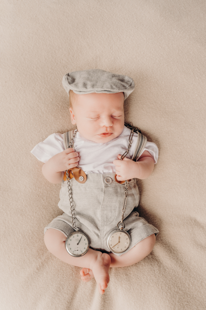 newborn in conductor outfit holding the pocket watches of his grand-father and late great-grandfather - newborn photography by Jamie Simmons