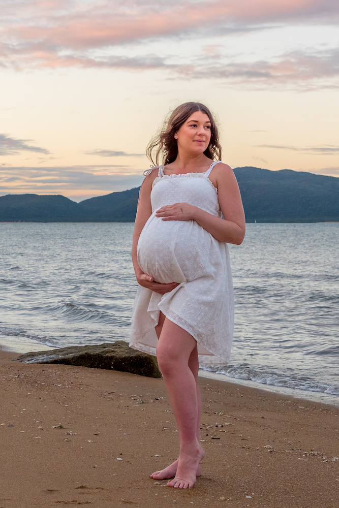 pregnant woman in white maternity gown on the beach at sunset - maternity photography by Jamie Simmons