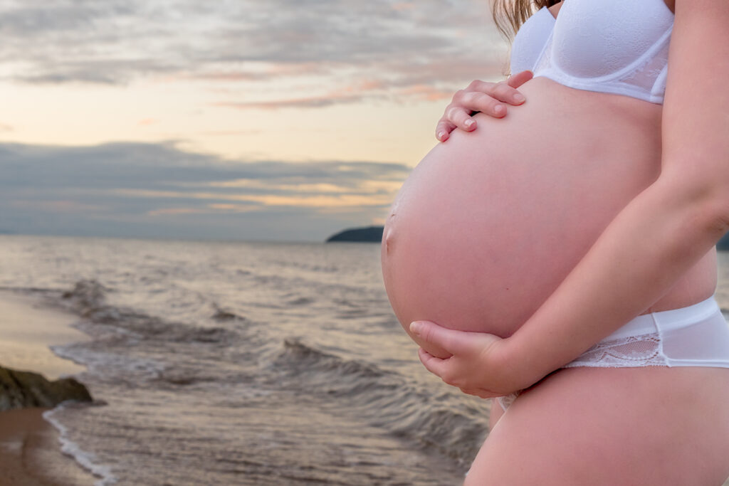 close-up of baby bump at sunset on the beach - maternity photography by Jamie Simmons