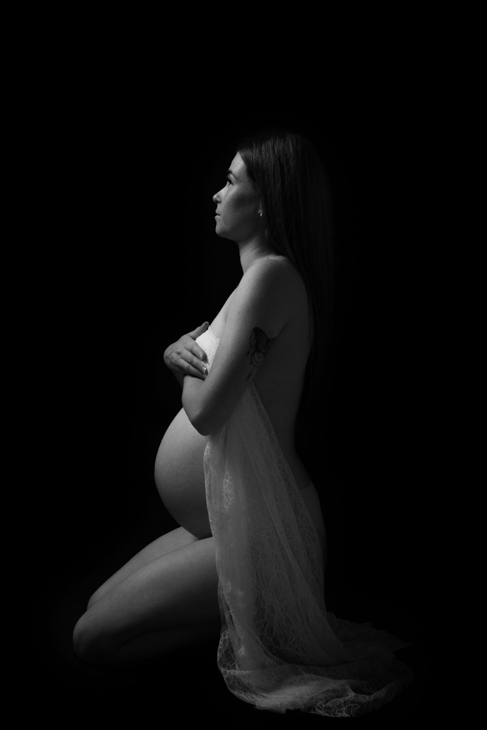 low light shot of pregnant woman empowering herself in studio maternity session showing off her raw baby belly - maternity photography by Jamie Simmons