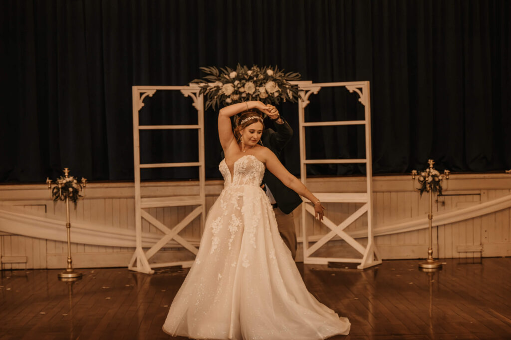 The bride and groom gracefully dance together in the heart of a charming room, creating a moment of joy and celebration. - Photo by Jamie Simmons