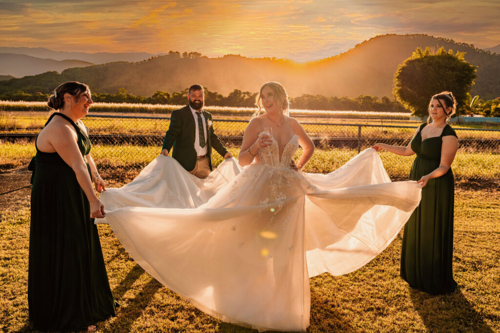 The bride and groom pose with their bridesmaids, capturing a joyful moment as the sun sets in the background. - Photo by Jamie Simmons